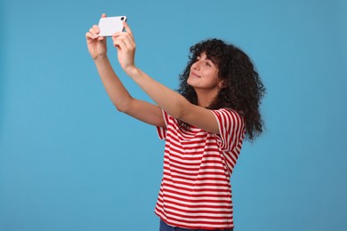 Photo of Beautiful young woman taking selfie on light blue background