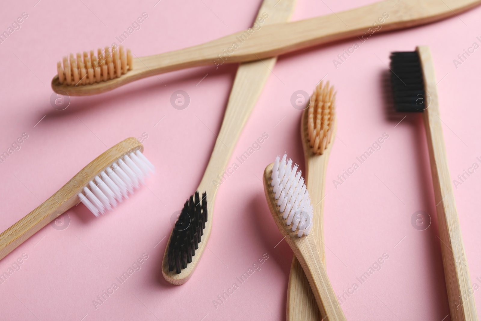 Photo of Many bamboo toothbrushes on pink background, closeup