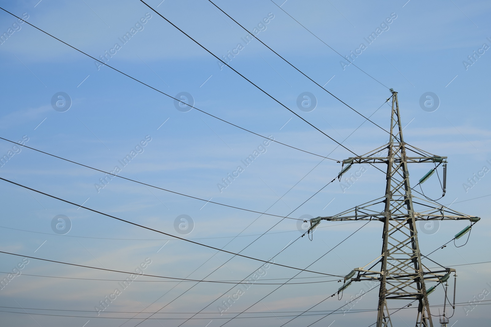 Photo of High voltage tower against blue sky on sunny day