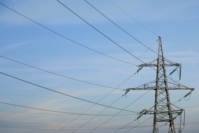 High voltage tower against blue sky on sunny day