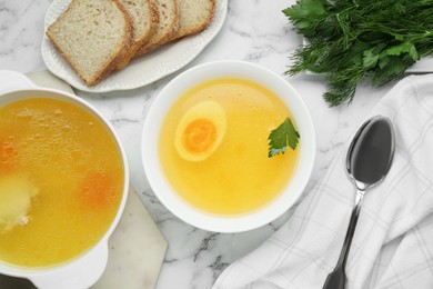 Photo of Delicious bouillon served on white marble table, flat lay
