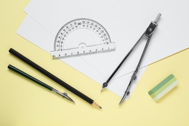Photo of Different rulers and compass on yellow background, flat lay