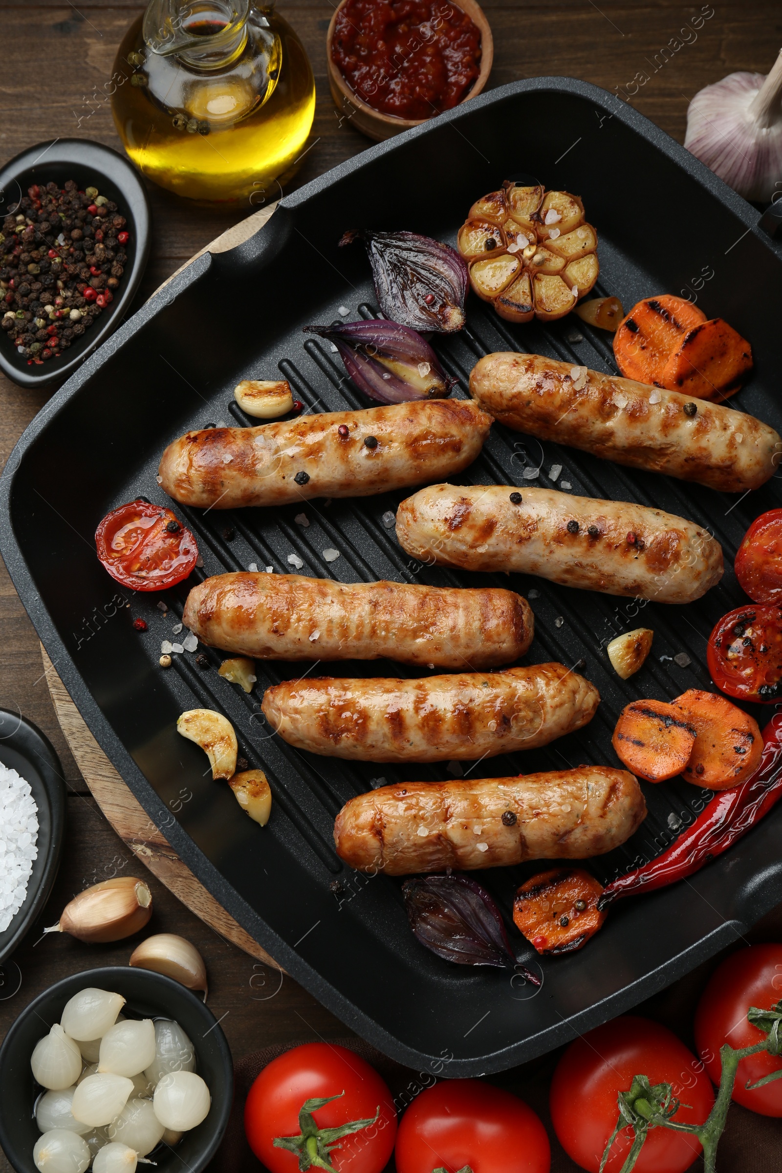 Photo of Tasty grilled sausages and ingredients on wooden table, flat lay