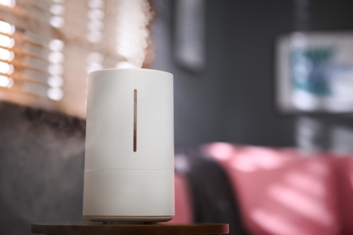 Photo of Modern air humidifier on table indoors. Space for text