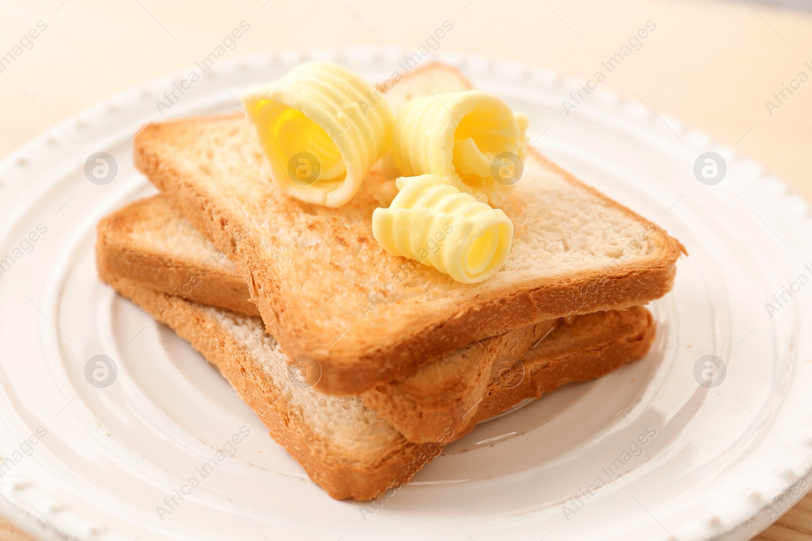 Photo of Toasted bread with butter curls on plate, closeup