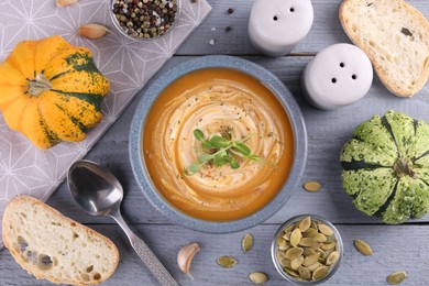Photo of Flat lay composition with bowl of delicious pumpkin soup on grey wooden table