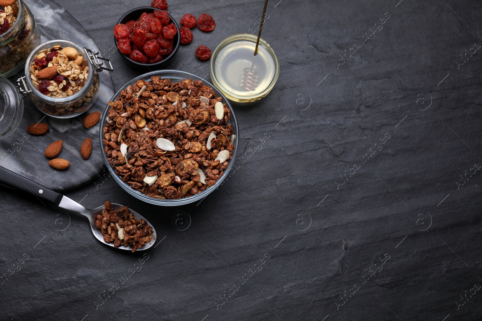 Photo of Tasty granola served with nuts and dry fruits on black table, flat lay. Space for text