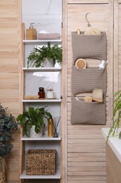 Photo of Shelving unit and organizer with essentials in bathroom. Stylish accessory