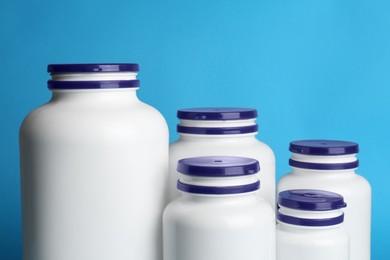 Photo of White medical bottles on light blue background, closeup