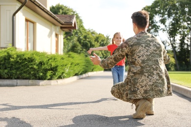 Father in military uniform and little daughter running to him outdoors