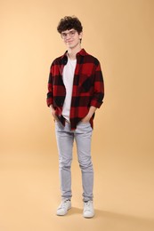 Teenage boy wearing glasses on beige background