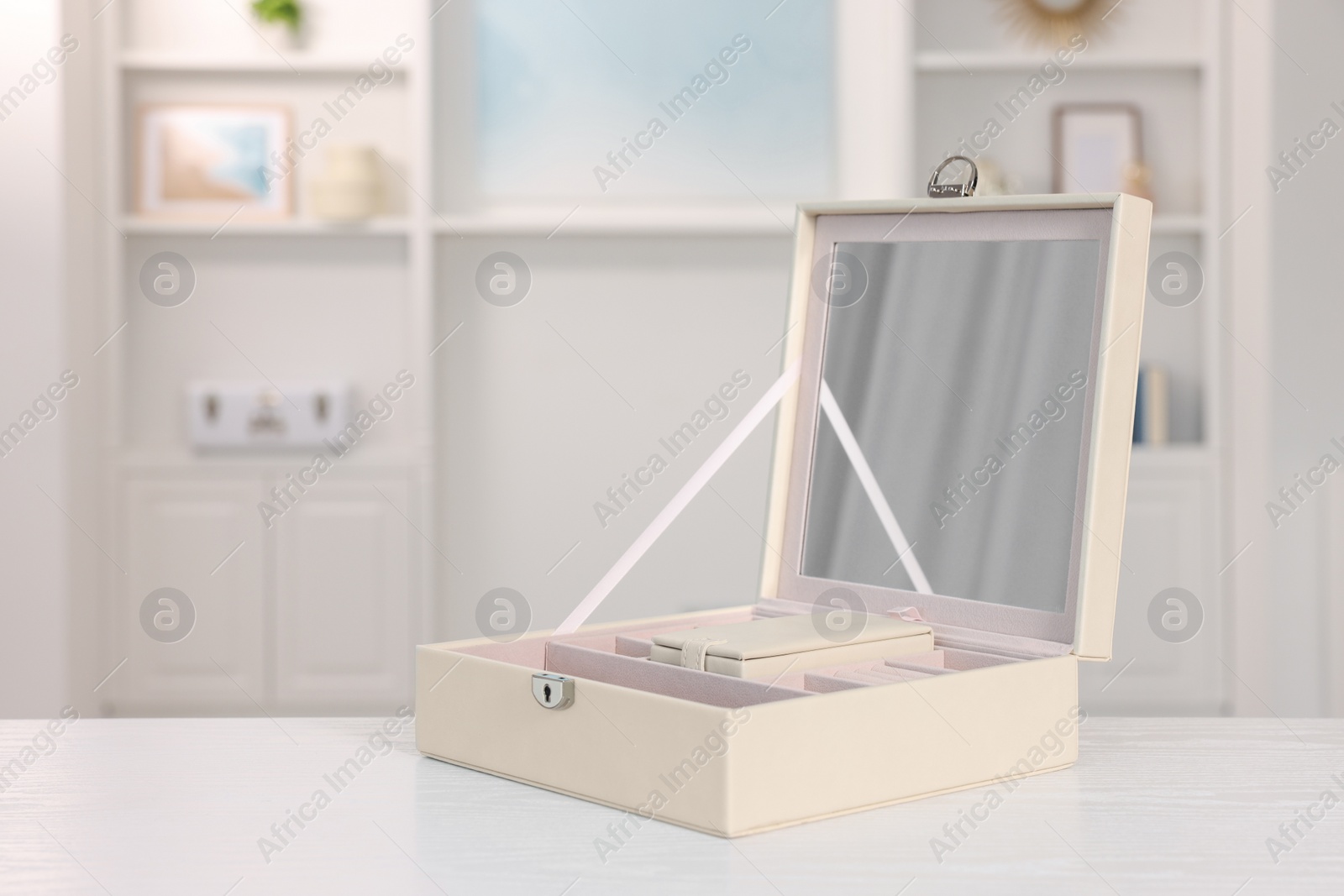 Photo of Empty jewelry box with mirror on white wooden table indoors. Space for text