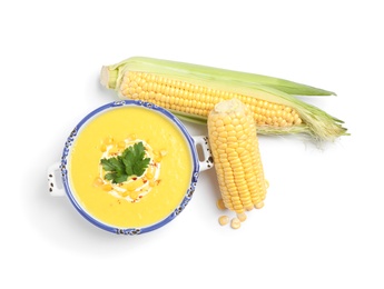 Photo of Delicious creamy corn soup and cobs isolated on white, top view