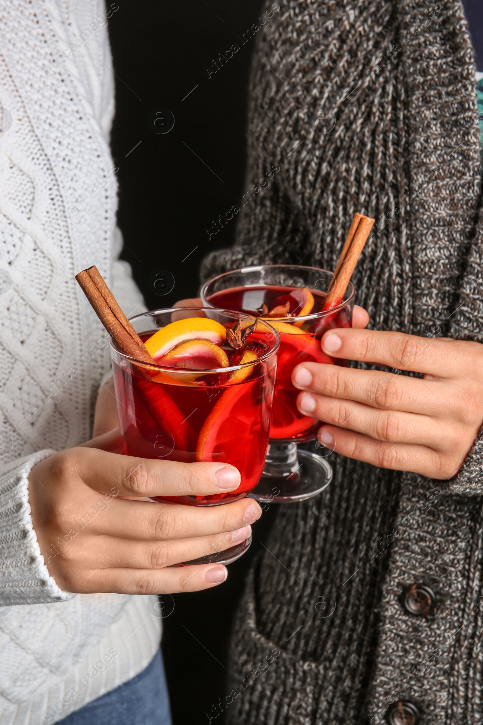 Photo of Man and woman holding glasses with hot mulled wine, closeup. Romantic holiday moment