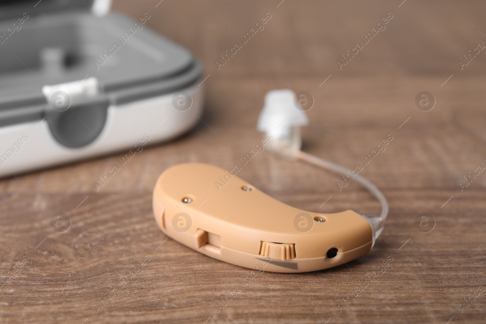 Photo of Hearing aid on wooden table, closeup. Medical device