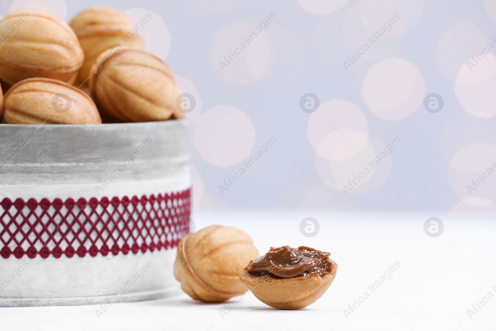 Photo of Homemade walnut shaped cookies with boiled condensed milk on white table, space for text. Bokeh effect