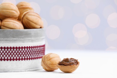 Homemade walnut shaped cookies with boiled condensed milk on white table, space for text. Bokeh effect