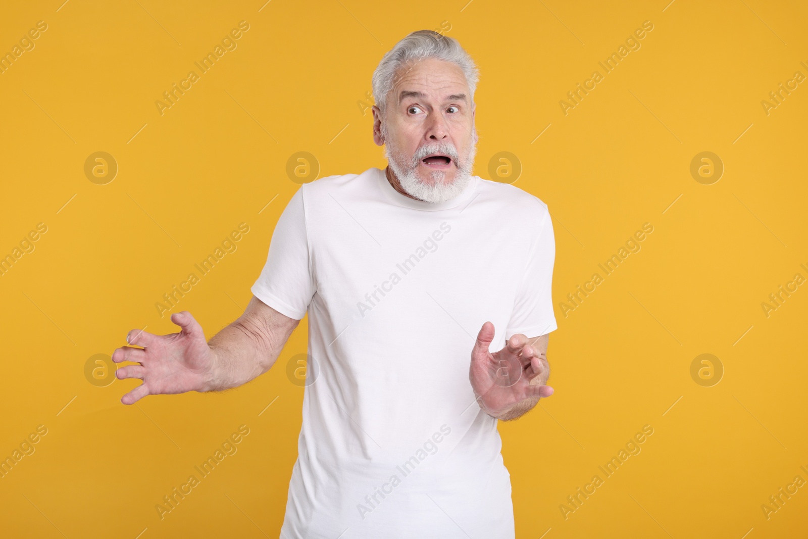 Photo of Portrait of surprised senior man on yellow background