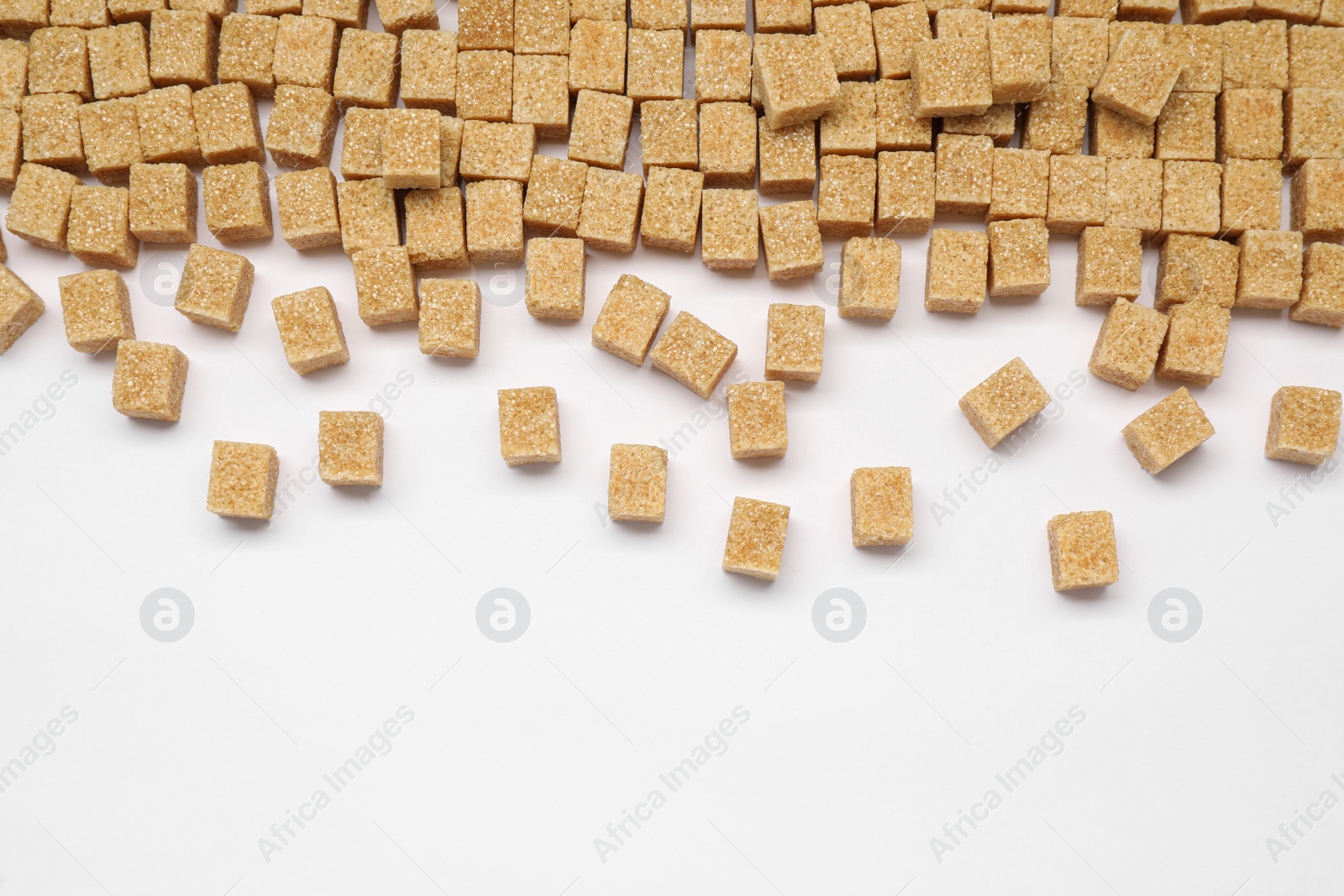 Photo of Brown sugar cubes on white background, flat lay. Space for text