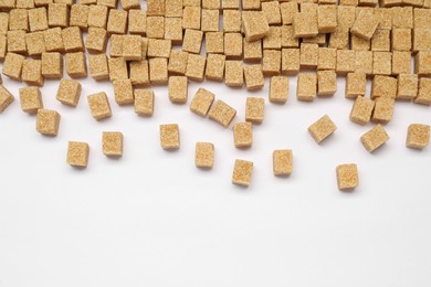 Photo of Brown sugar cubes on white background, flat lay. Space for text