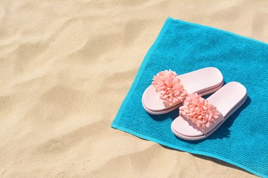 Photo of Towel and stylish slippers on sand, space for text. Beach accessories
