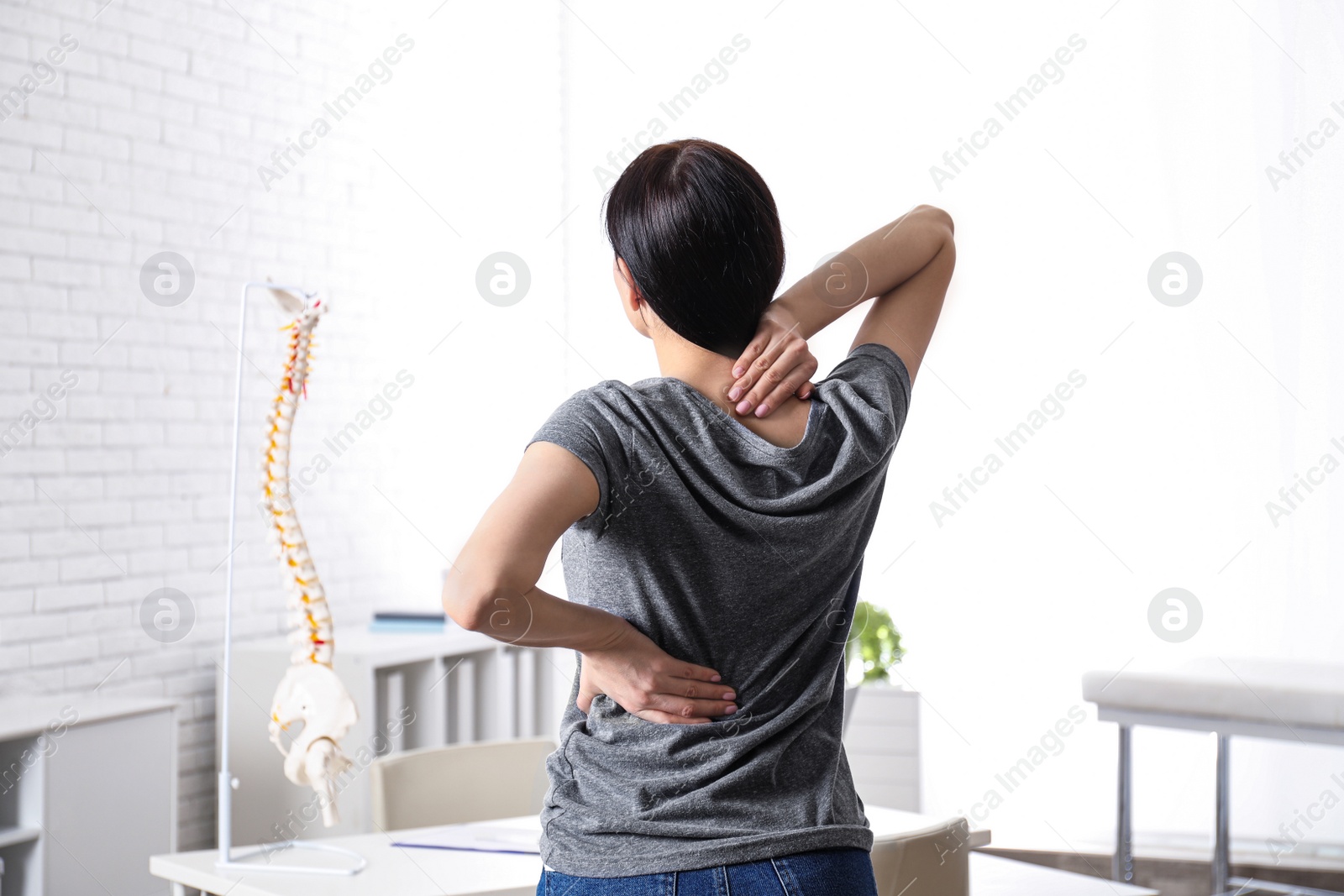 Photo of Woman suffering from pain in back at clinic. Visiting orthopedist