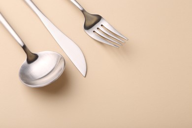 Photo of Stylish cutlery set on beige table, closeup. Space for text