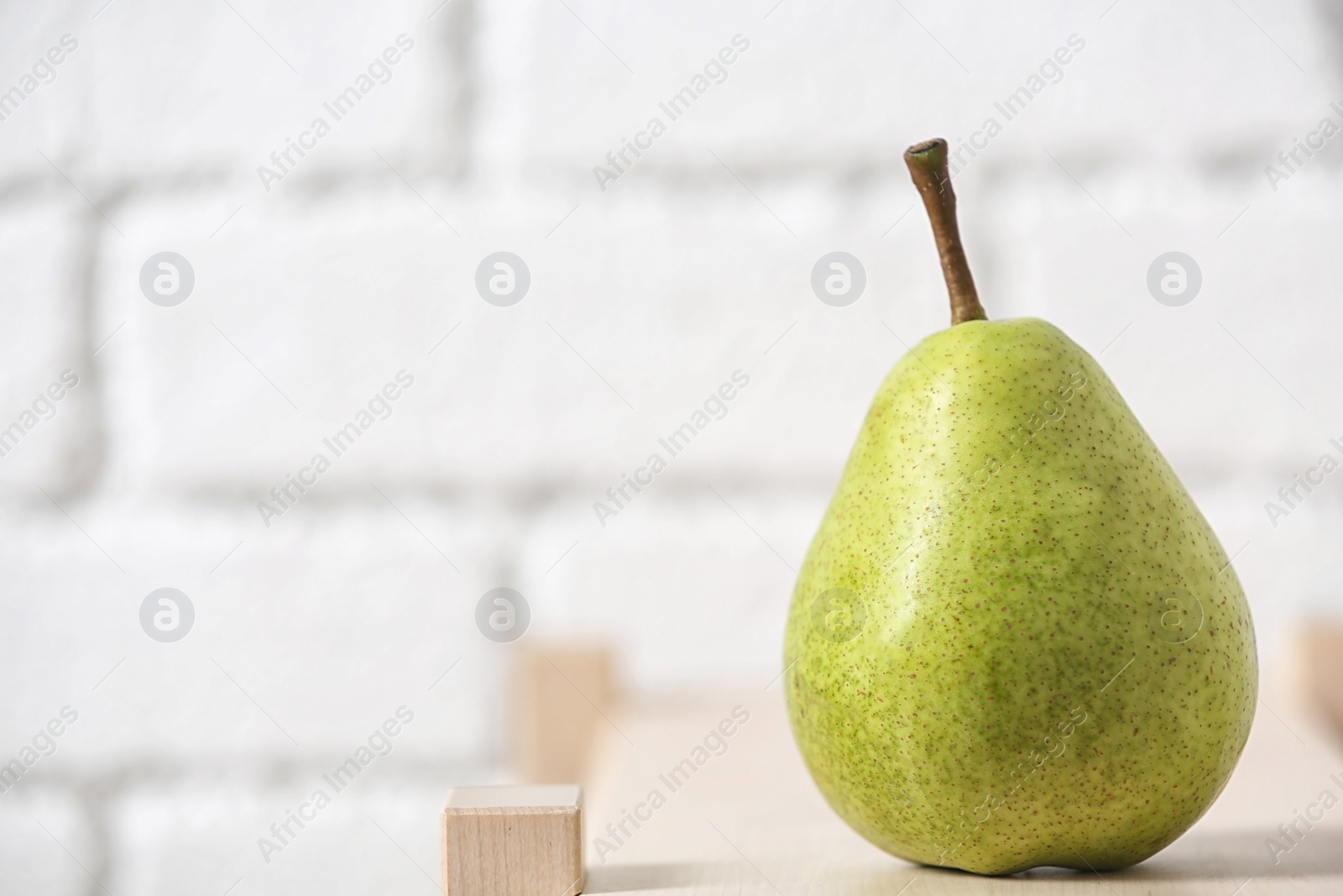 Photo of Ripe pear on wooden shelf against blurred background. Space for text