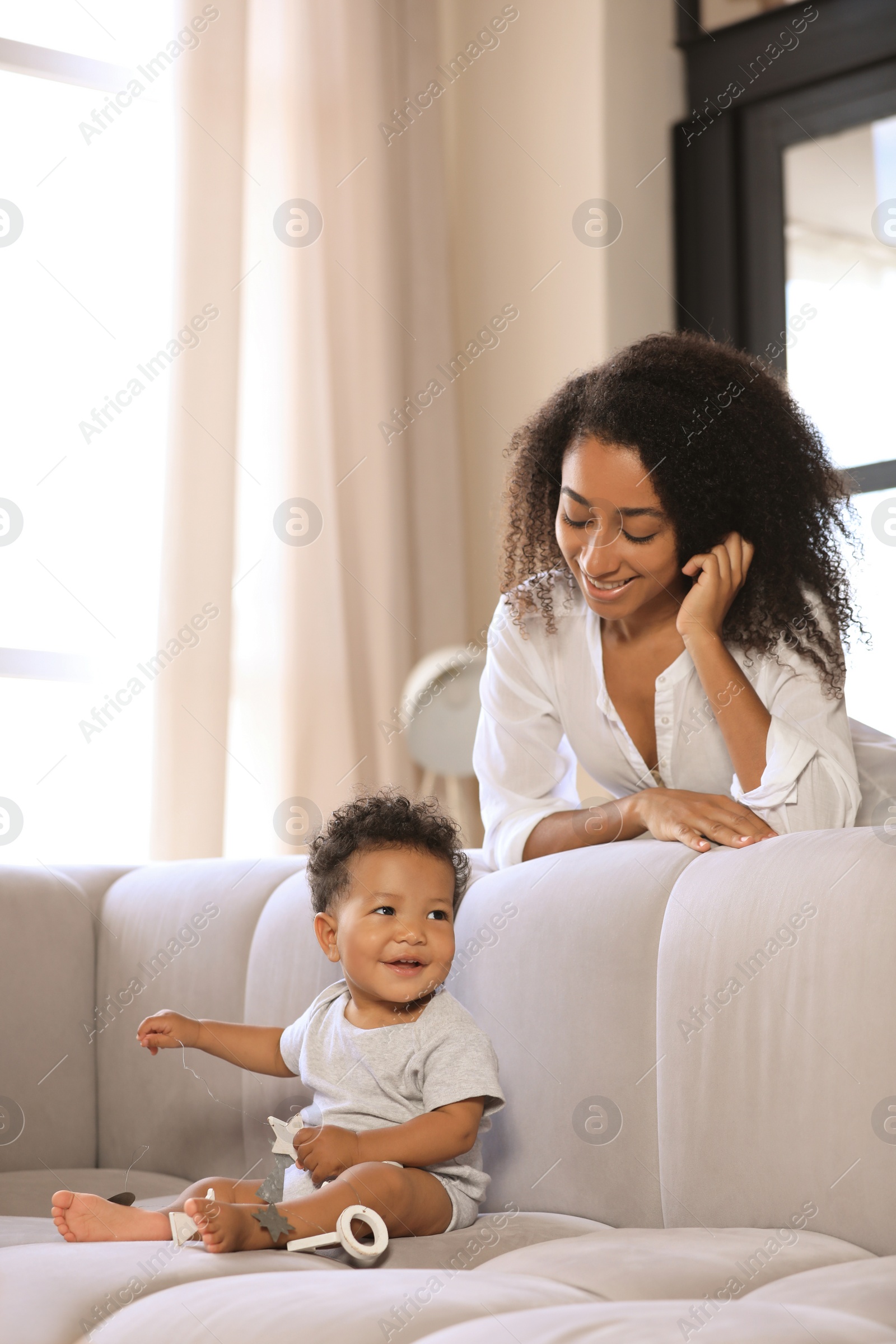 Photo of African-American woman with her baby in living room. Happiness of motherhood