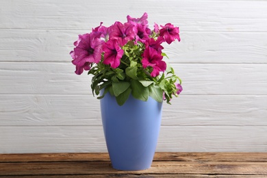 Photo of Beautiful pink petunia flowers in plant pot on wooden table against white background