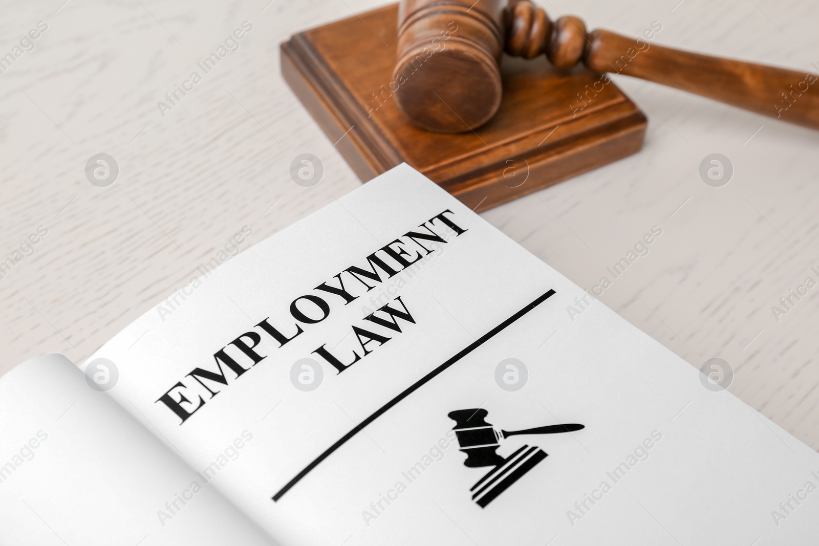 Photo of Open book with words EMPLOYMENT LAW and gavel on table, closeup