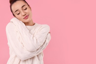 Photo of Beautiful young woman in stylish warm sweater on pink background, space for text
