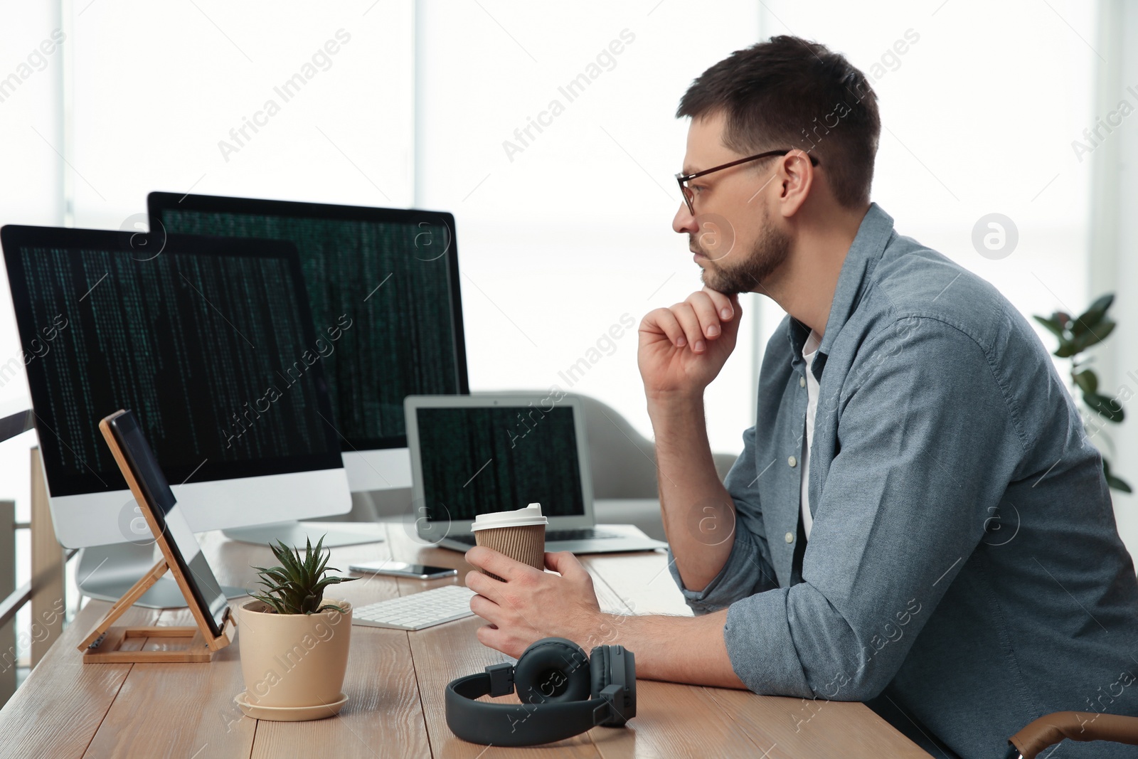 Photo of Programmer with coffee working at desk in office