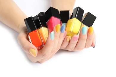 Photo of Woman holding bottles of nail polish on white background, closeup