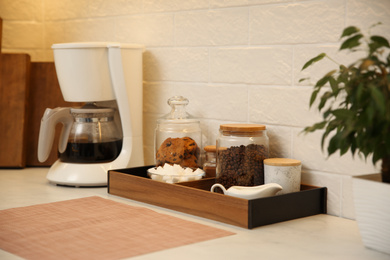 Modern coffeemaker on countertop near white brick wall in kitchen