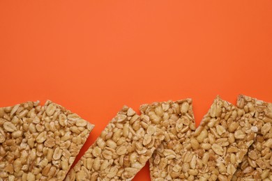 Tasty peanut bars (kozinaki) on orange background, flat lay. Space for text