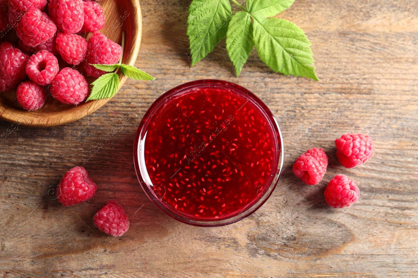 Image of Sweet raspberry jam and fresh berries on wooden table, flat lay