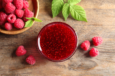 Sweet raspberry jam and fresh berries on wooden table, flat lay