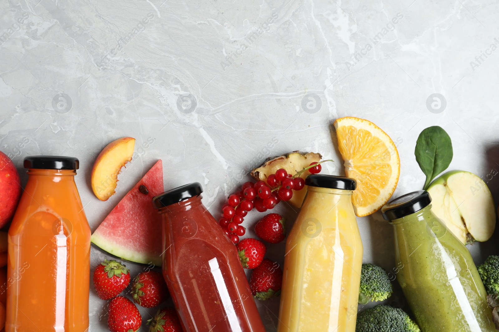 Photo of Bottles of delicious juices and fresh fruits on marble table, flat lay. Space for text