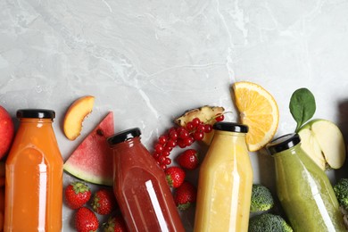 Bottles of delicious juices and fresh fruits on marble table, flat lay. Space for text