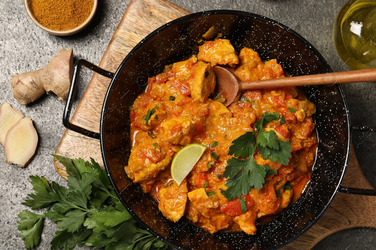 Photo of Delicious chicken curry and ingredients on grey table, flat lay