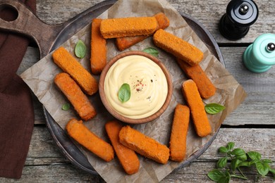 Photo of Delicious chicken nuggets and cheese sauce with basil on wooden table, flat lay