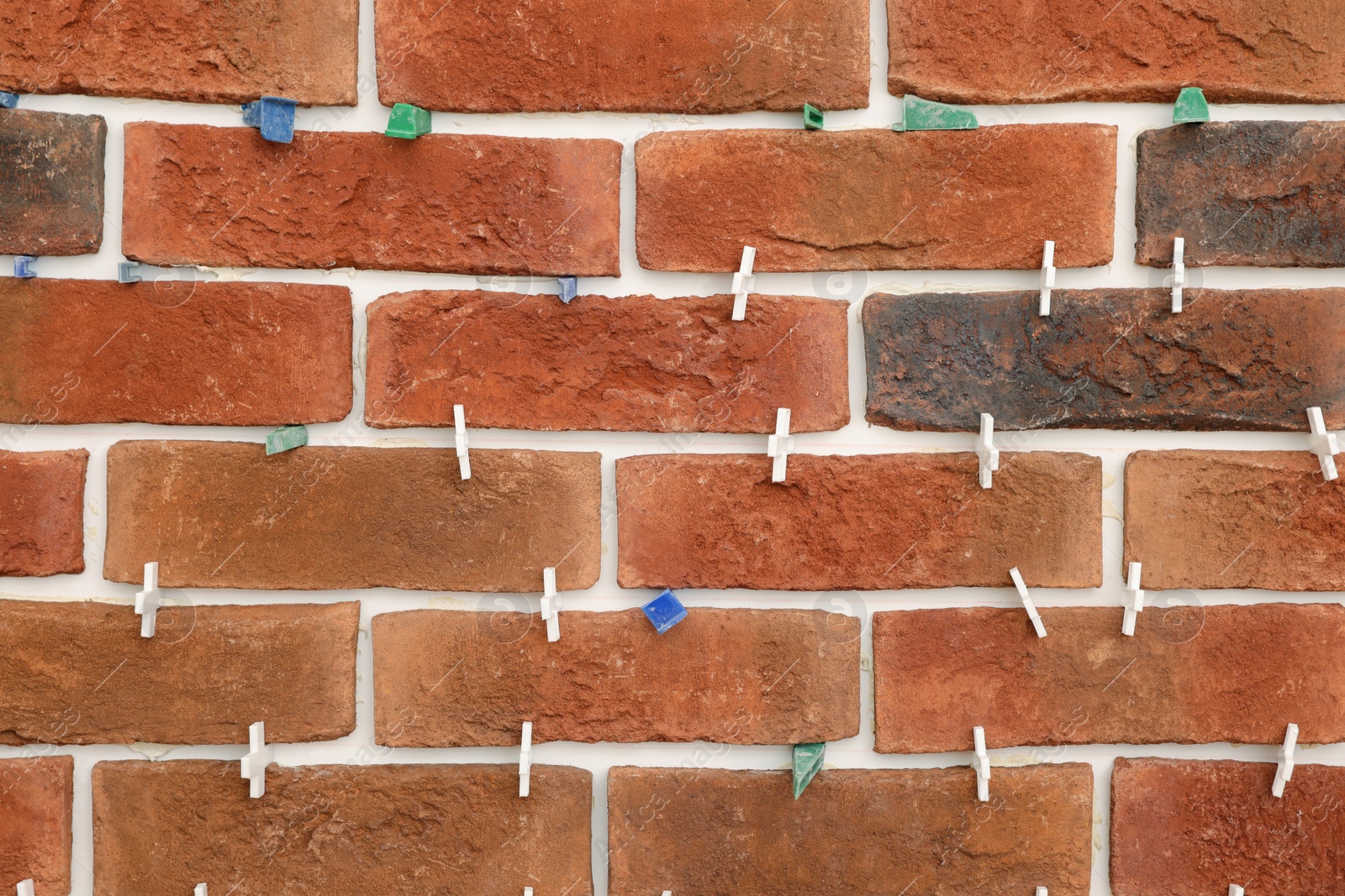 Photo of Decorative bricks with tile leveling system on wall