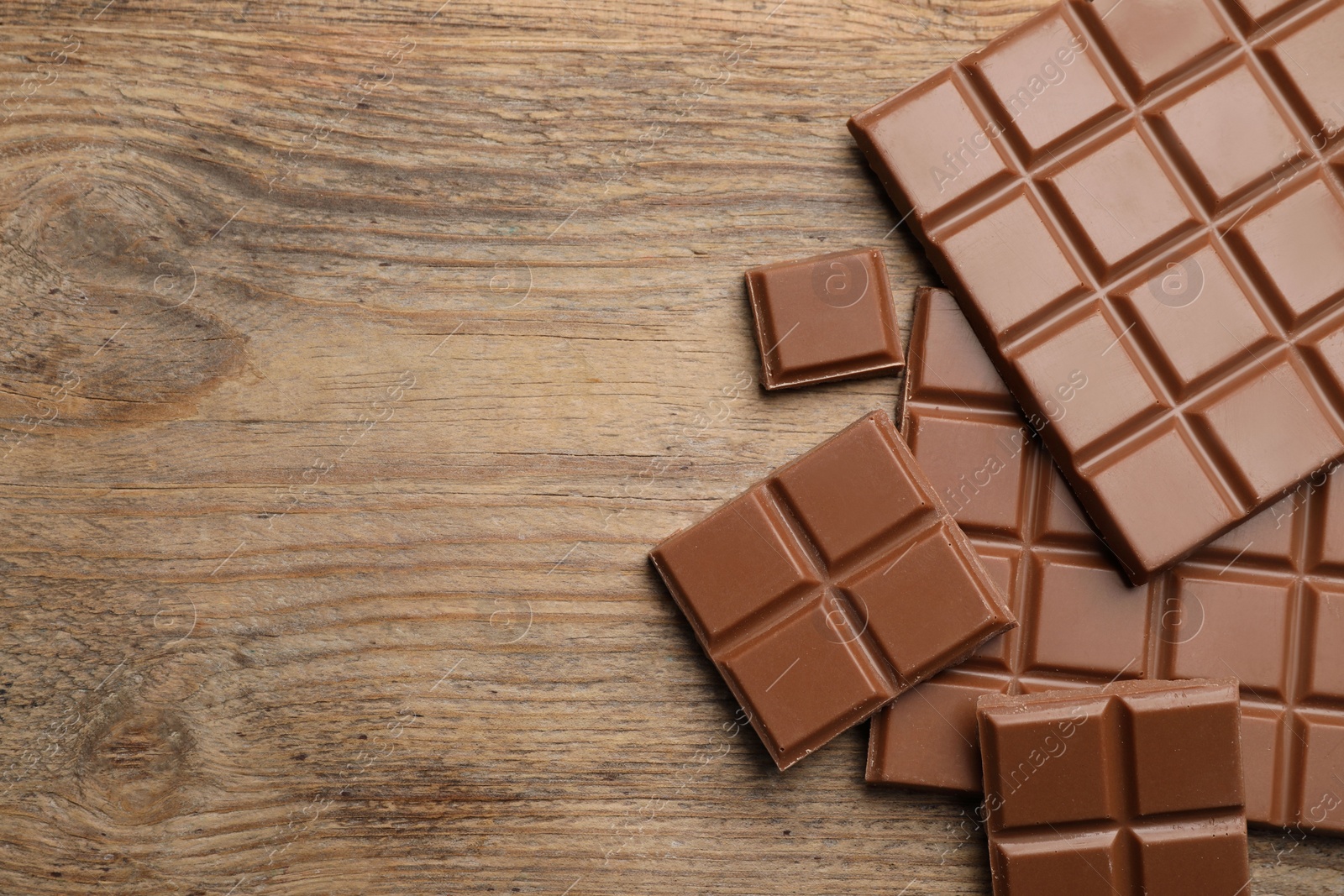 Photo of Delicious milk chocolate on wooden table, flat lay. Space for text