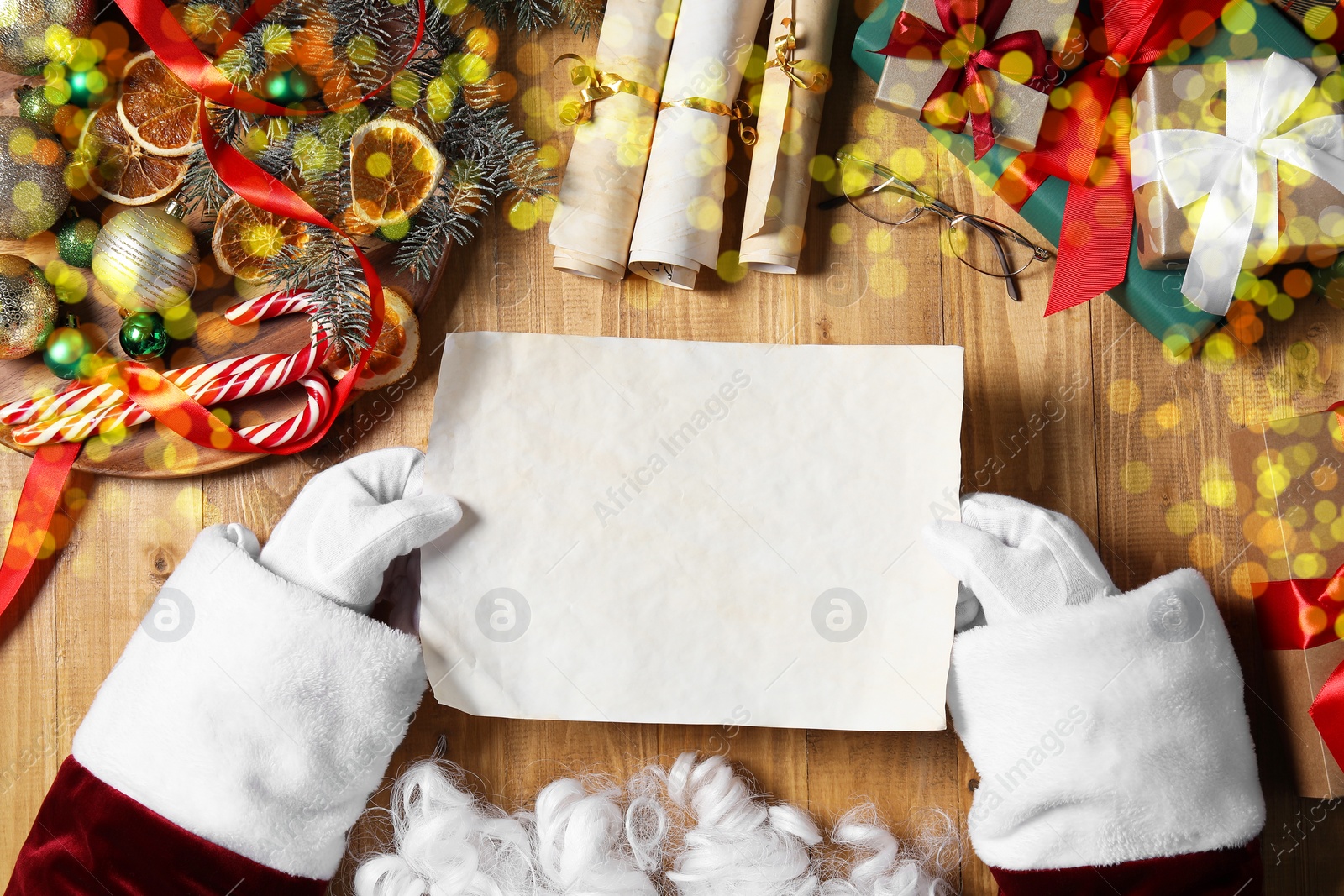 Photo of Santa Claus with letter, eyeglasses and Christmas decor at wooden table, top view. Space for text