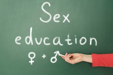 Image of Sex Education. Woman drawing male gender sign on green chalkboard, closeup