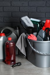 Photo of Different car cleaning products on grey table near black brick wall