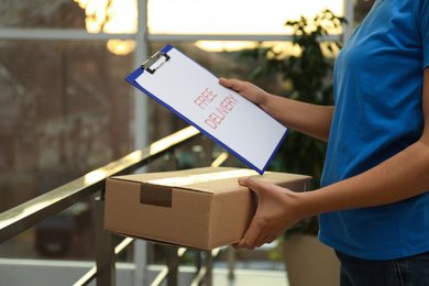 Courier with clipboard holding parcel indoors, closeup