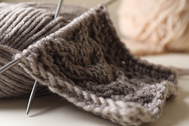Knitting, soft yarn and needles on beige background, closeup