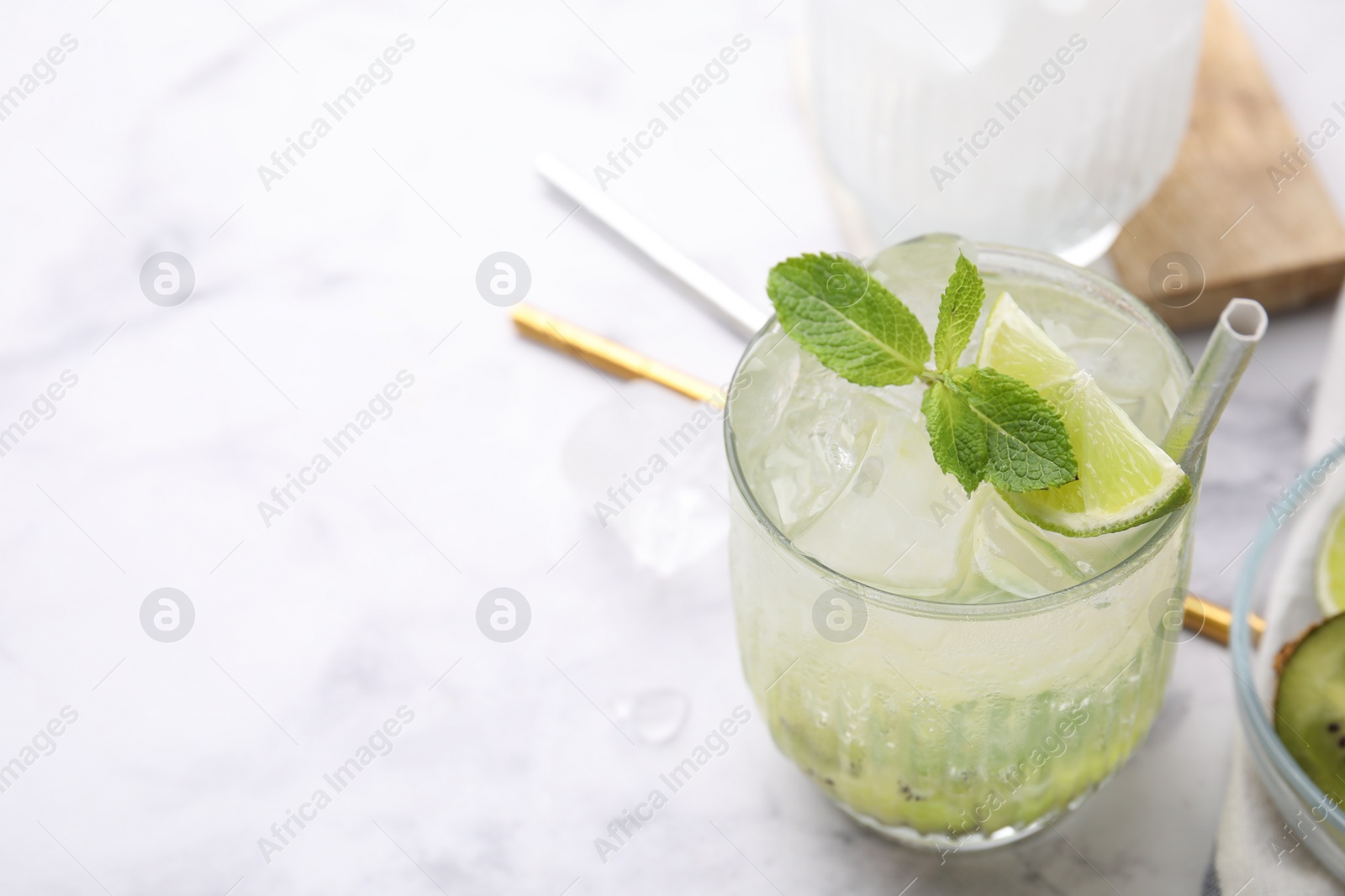 Photo of Glass of refreshing drink with lime and mint on white table, closeup. Space for text